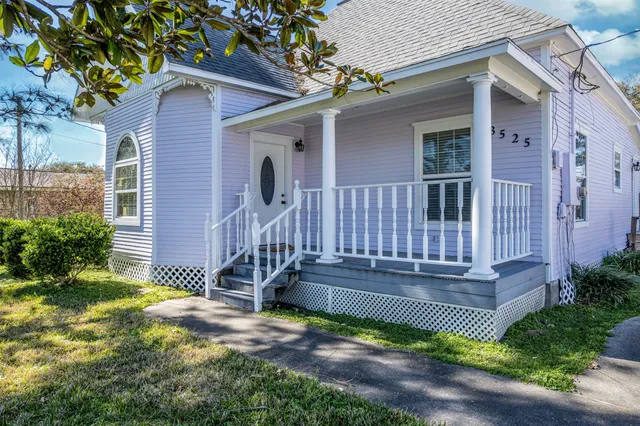 a view of a house with wooden fence next to a yard
