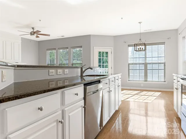 a kitchen with granite countertop a sink and white cabinets