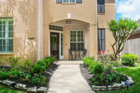 a front view of a house with a garden and trees