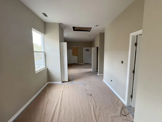 a view of a hallway with wooden floor and a bathroom