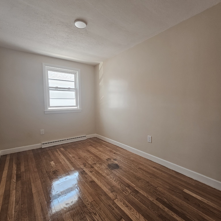 131 Itasca Street, Unit 2 Boston, MA 02126 - Photo 13 of 16 an empty room with wooden floor and windows