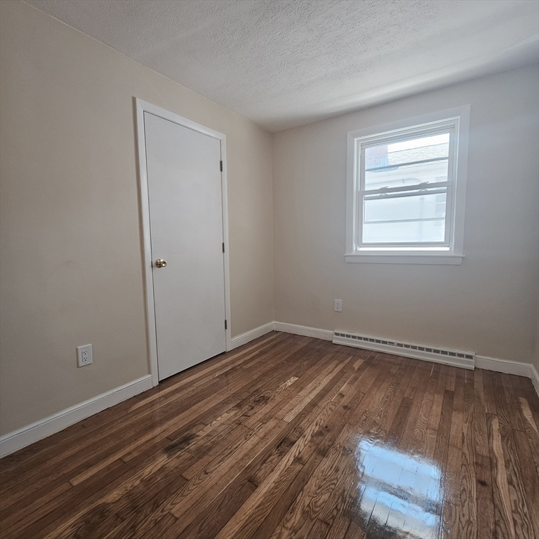 131 Itasca Street, Unit 2 Boston, MA 02126 - Photo 14 of 16 a view of an empty room with wooden floor and a window