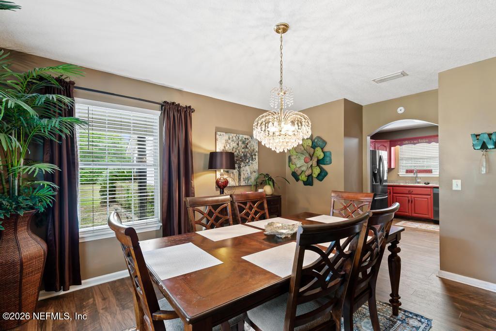 28317 Pike Road Hilliard, FL 32046 - Photo 11 of 42 a view of a dining room and a livingroom with furniture wooden floor a chandelier