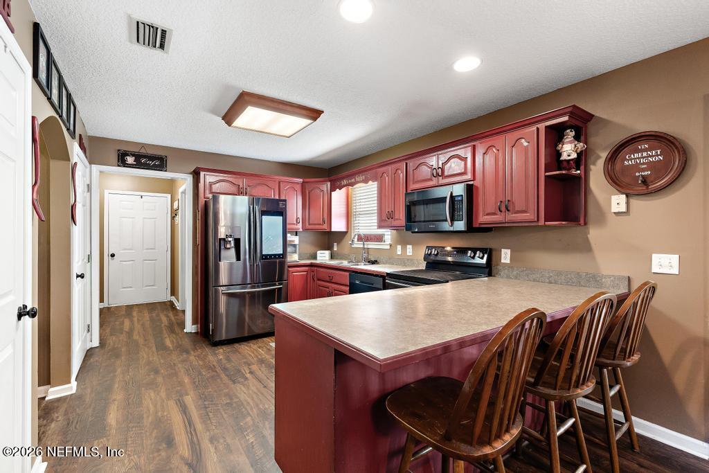 28317 Pike Road Hilliard, FL 32046 - Photo 18 of 42 a kitchen with stainless steel appliances granite countertop a refrigerator a stove top oven a sink dishwasher and wooden cabinets