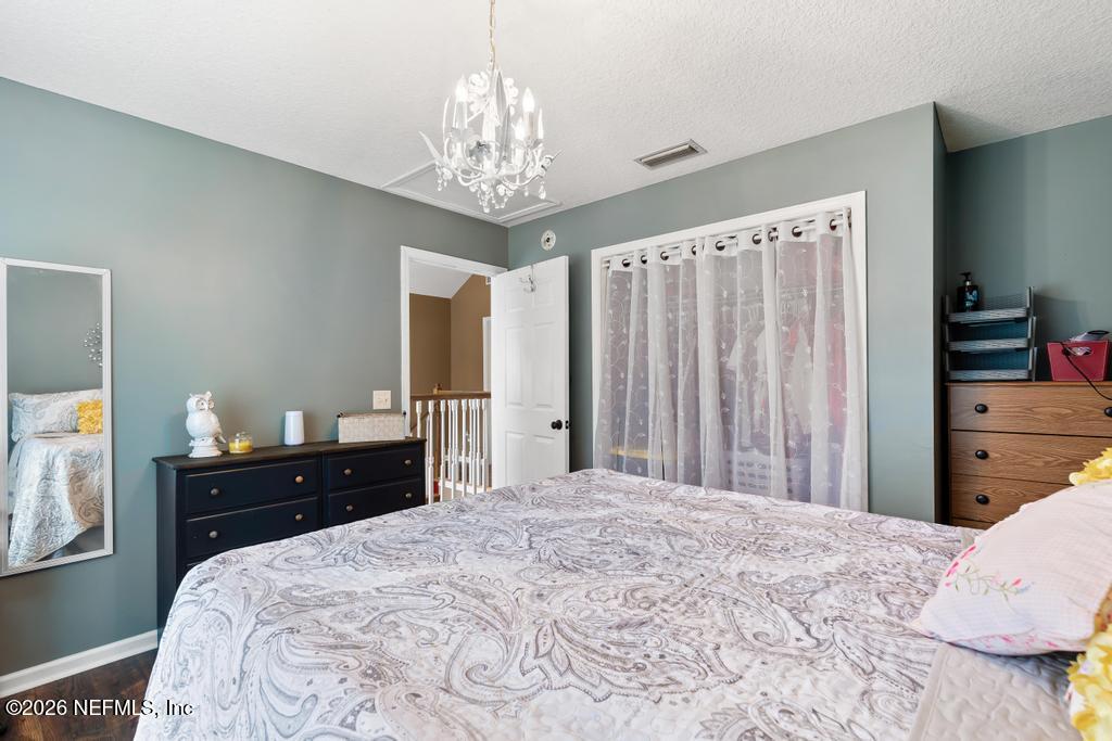 28317 Pike Road Hilliard, FL 32046 - Photo 30 of 42 a bedroom with a bed and a chandelier