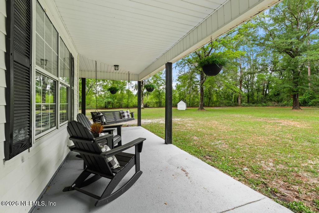 28317 Pike Road Hilliard, FL 32046 - Photo 3 of 42 a view of a patio with table and chairs potted plants with wooden floor and fence