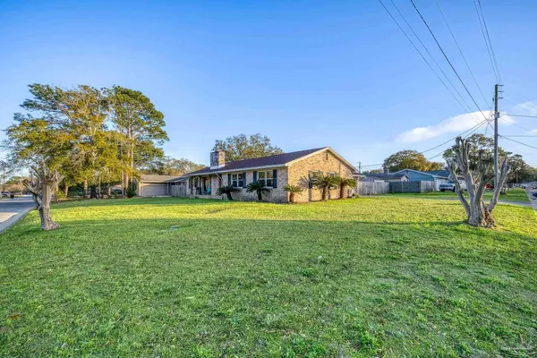 a front view of house with yard and trees in the background