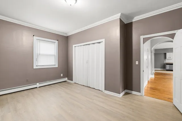 a view of an empty room with window and a kitchen
