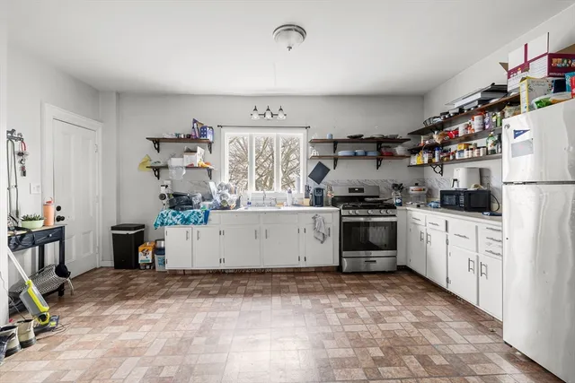 a kitchen with a refrigerator and white cabinets