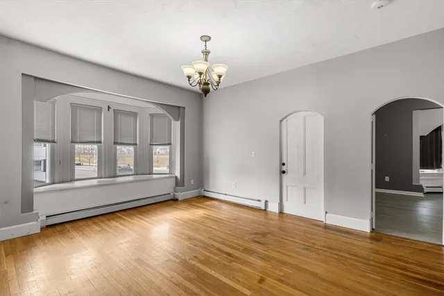 a view of an empty room with glass door and wooden floor