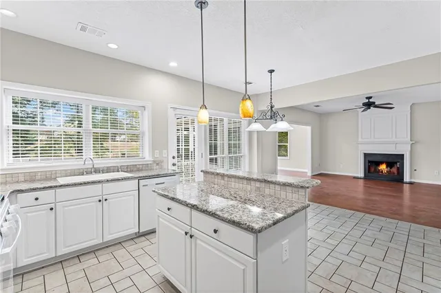 a open kitchen with granite countertop a stove a sink and a wooden floor