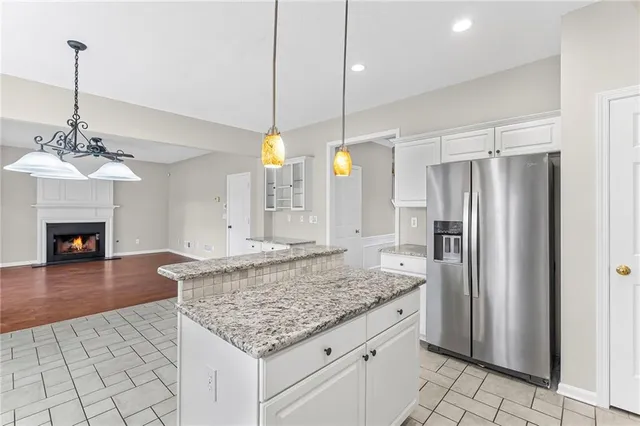 a kitchen with kitchen island granite countertop a refrigerator a chandelier and stove