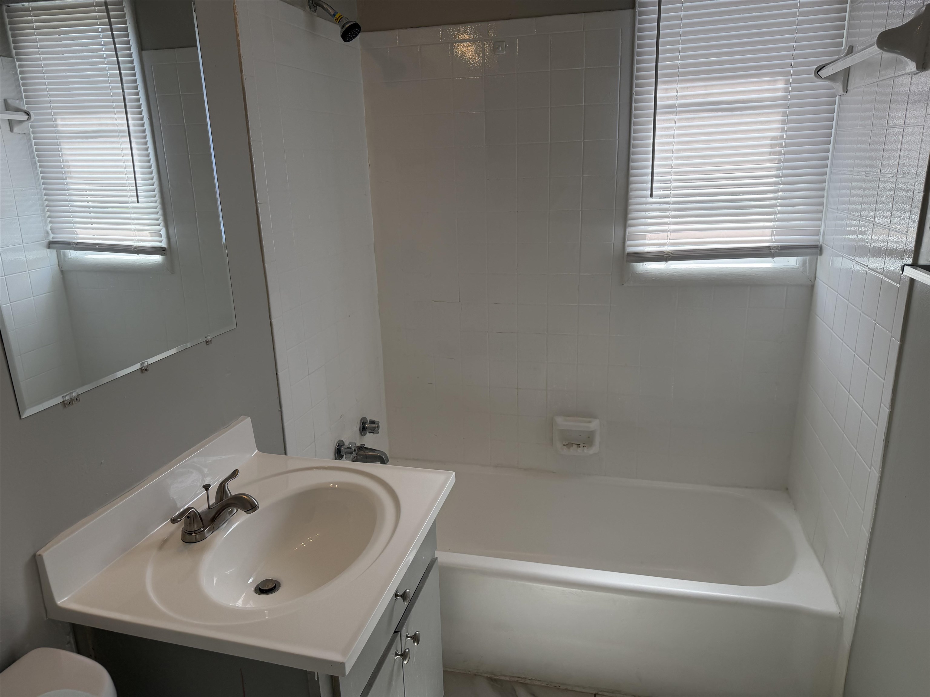 3525 Rochester Road Memphis, TN 38109 - Photo 10 of 10 Bathroom featuring a white bathtub with subway tile surround, single vanity with integrated sink, chrome faucet, and a wall-mounted mirror