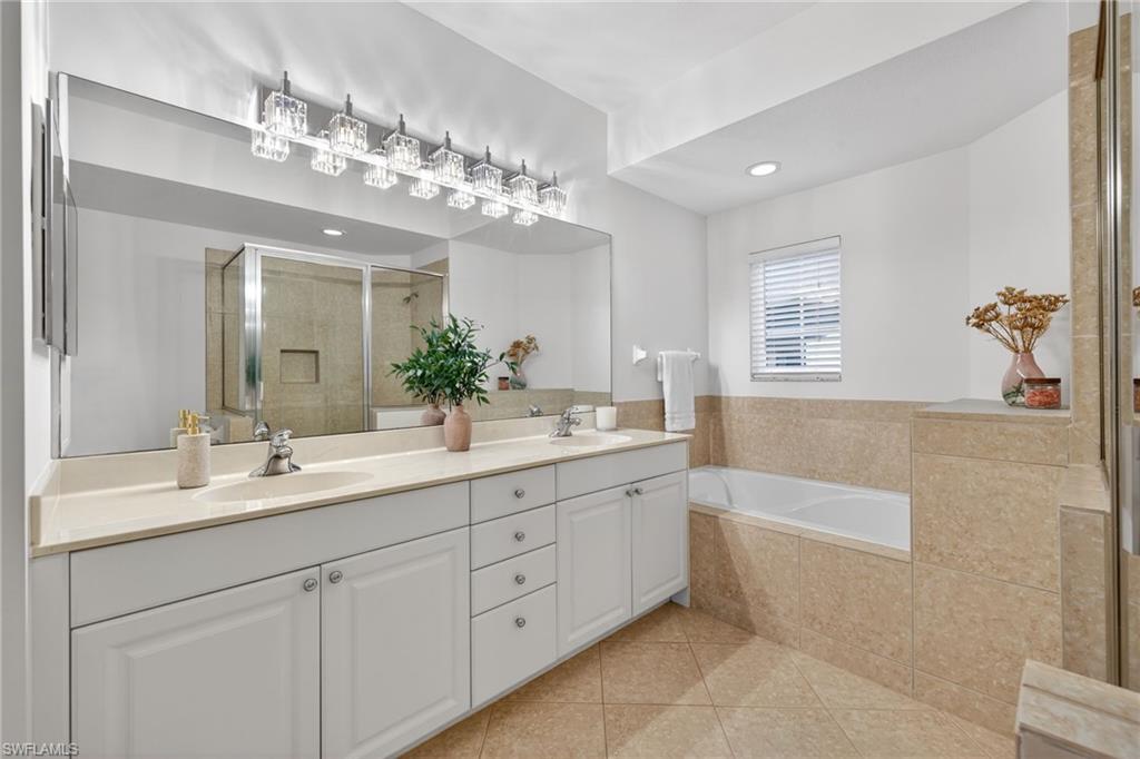 9201 Palmetto Ridge Drive, Unit 101 Estero, FL 34135 - Photo 15 of 29 Bathroom with a stall shower, double vanity, a garden tub, and light tile patterned floors