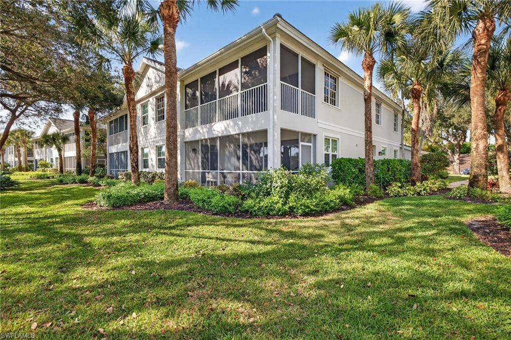 9201 Palmetto Ridge Drive, Unit 101 Estero, FL 34135 - Photo 23 of 29 Rear view of property featuring a sunroom, a lawn, and a balcony