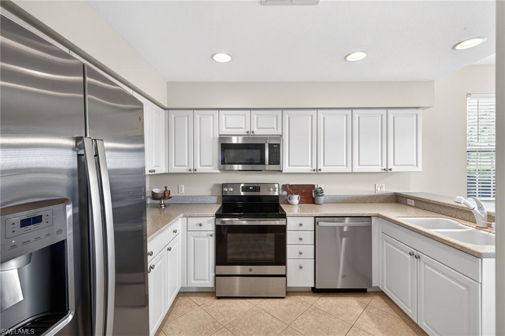 9201 Palmetto Ridge Drive, Unit 101 Estero, FL 34135 - Photo 9 of 29 Kitchen featuring stainless steel appliances, white cabinets, recessed lighting, light tile patterned floors, and a peninsula