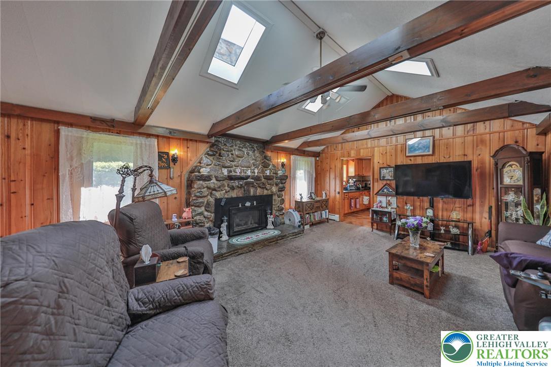 331 Cranberry Creek Road Cresco, PA 18326 - Photo 15 of 95 A rustic living room with exposed wood beams and a large stone fireplace provides a cozy, inviting atmosphere.