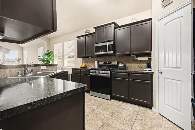 a kitchen with granite countertop a refrigerator a sink and wooden cabinets