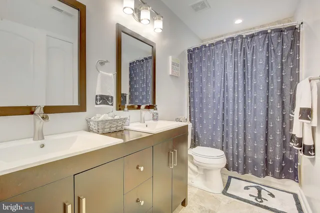a bathroom with a double vanity sink toilet and a mirror