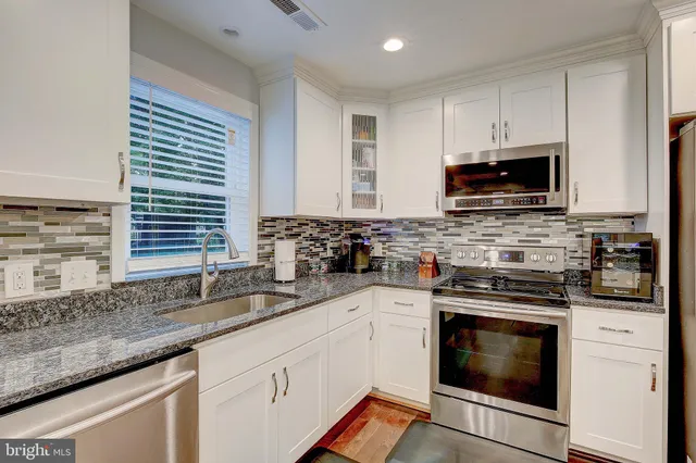 a kitchen with granite countertop a sink stainless steel appliances and cabinets