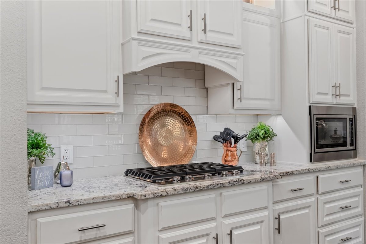 15519 Stallion Point Circle Cypress, TX 77429 - Photo 11 of 37 The kitchen features white cabinetry, a built-in microwave, a gas range, and a subway tile backsplash