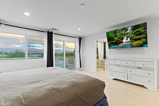 a spacious bedroom with a large bed and a flat tv screen on dresser
