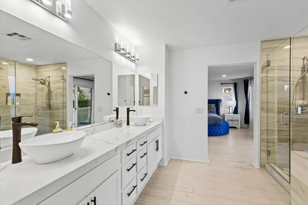 a bathroom with a double vanity sink a toilet a glass door and shower