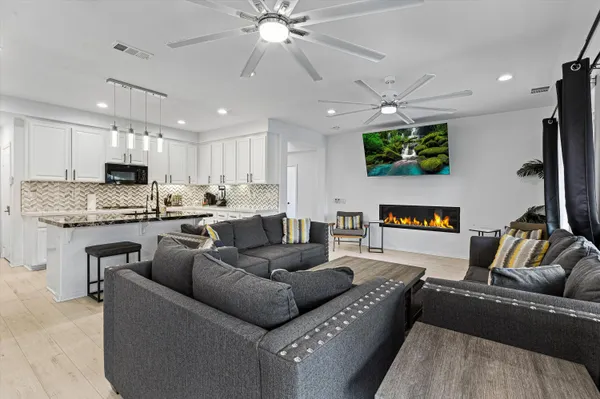 a living room with furniture and a flat screen tv with kitchen view