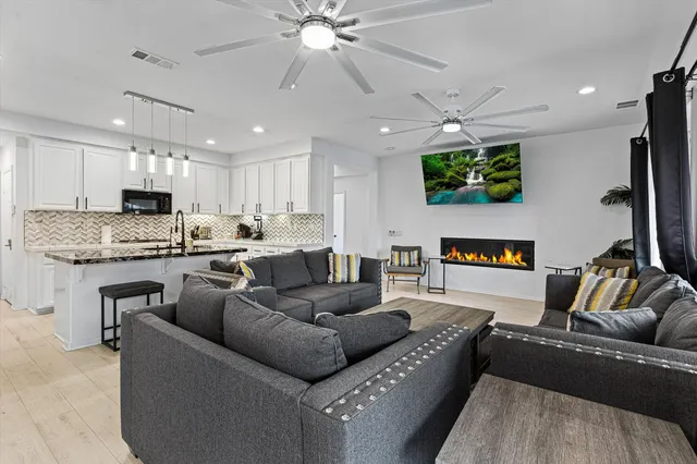 a living room with furniture and a flat screen tv with kitchen view