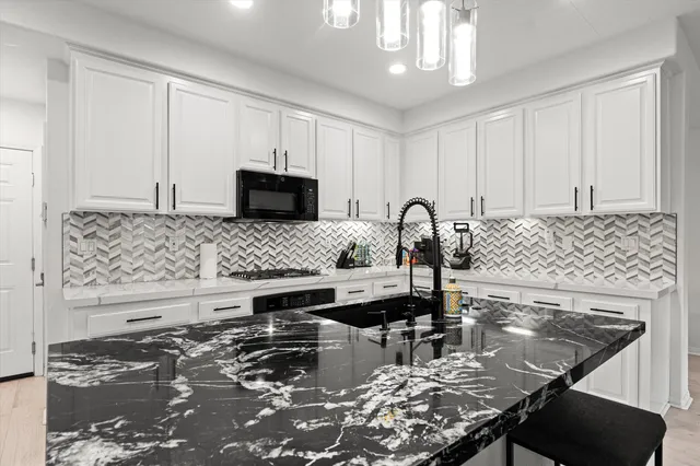 a kitchen with granite countertop a stove a sink and a microwave