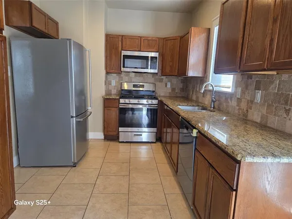 a kitchen with granite countertop a refrigerator and a sink