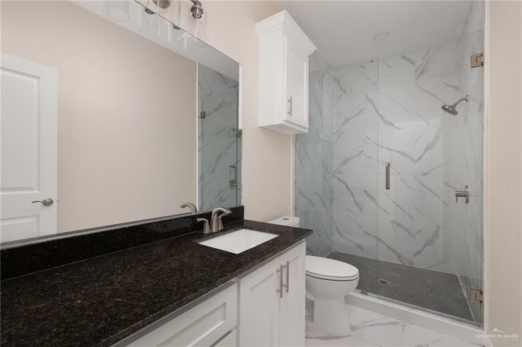 602 Mountain Road, Unit 12B Mission, TX 78573 - Photo 5 of 10 a bathroom with a granite countertop sink toilet a mirror and shower
