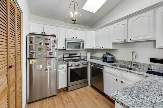 a kitchen with stainless steel appliances granite countertop a refrigerator a stove a sink dishwasher a dining table and chairs with wooden floor