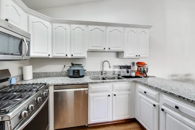 a kitchen with white cabinets and appliances