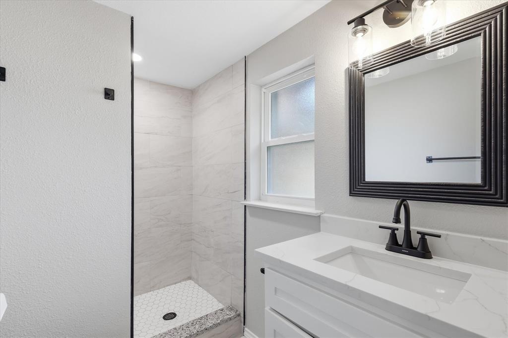 857 Twilight Trail Grapevine, TX 76051 - Photo 27 of 35 Contemporary bathroom featuring a white vanity with an integrated sink, a dark framed mirror, and a three-light fixture