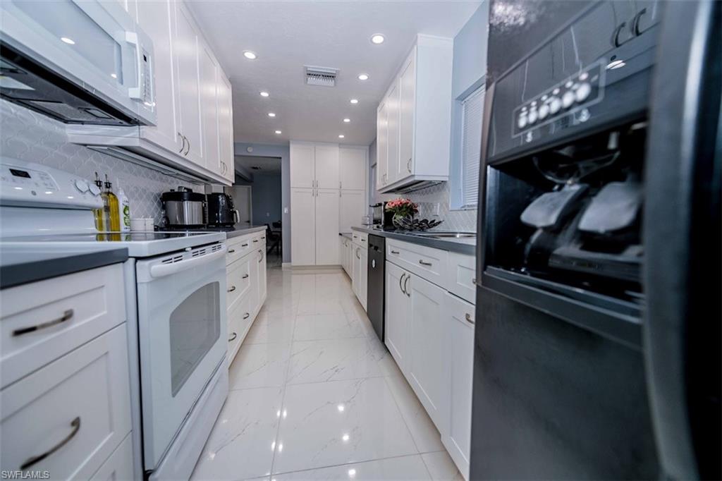 2137 44th Street Southwest Naples, FL 34116 - Photo 23 of 50 Kitchen featuring tasteful backsplash, white cabinetry, marble finish floor, and white appliances