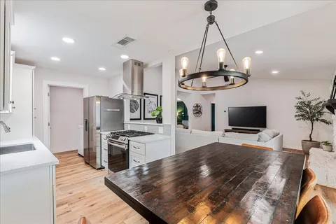 a kitchen with stainless steel appliances granite countertop a stove a refrigerator a sink a microwave a dining table and chairs