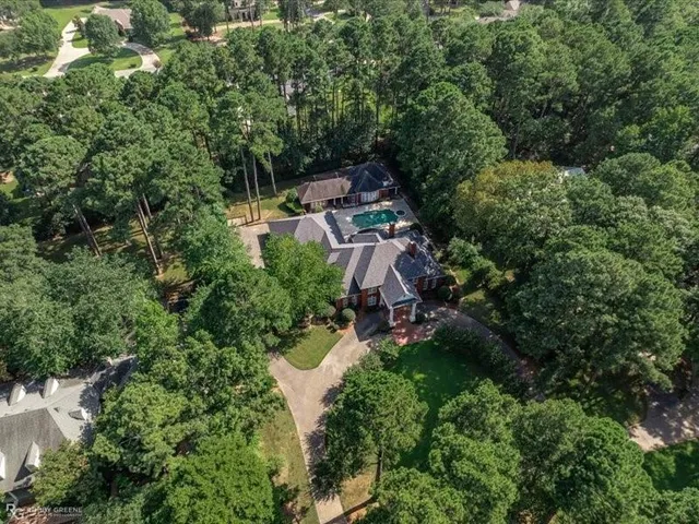 an aerial view of residential house with outdoor space and trees all around