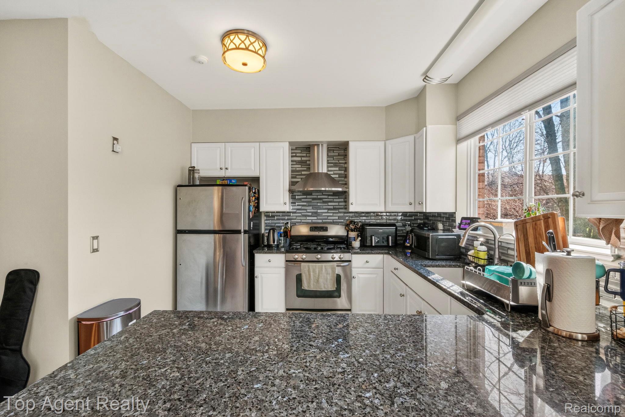 41567 Glade Road, Unit 20 Canton, MI 48187 - Photo 15 of 47 Kitchen featuring stainless steel appliances, white cabinets, decorative backsplash, dark stone countertops, and a peninsula