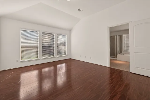 a view of an empty room with wooden floor and windows