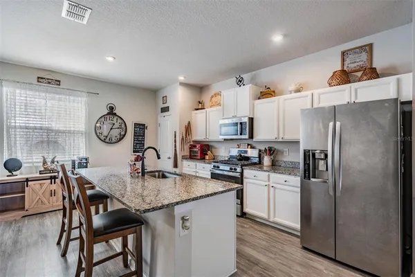 a kitchen with stainless steel appliances granite countertop a dining table chairs stove and cabinets
