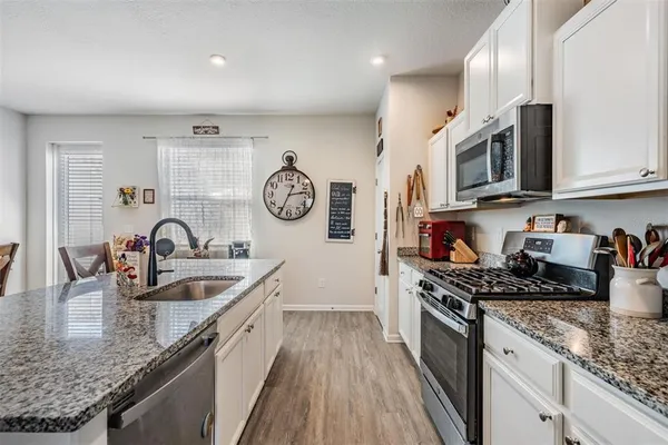 a kitchen with stainless steel appliances granite countertop a stove a sink dishwasher and cabinets with wooden floor
