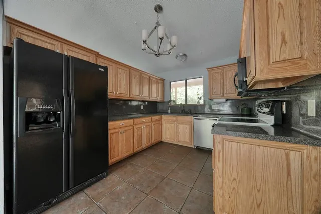 a kitchen with stainless steel appliances granite countertop a refrigerator a sink dishwasher a stove and white cabinets
