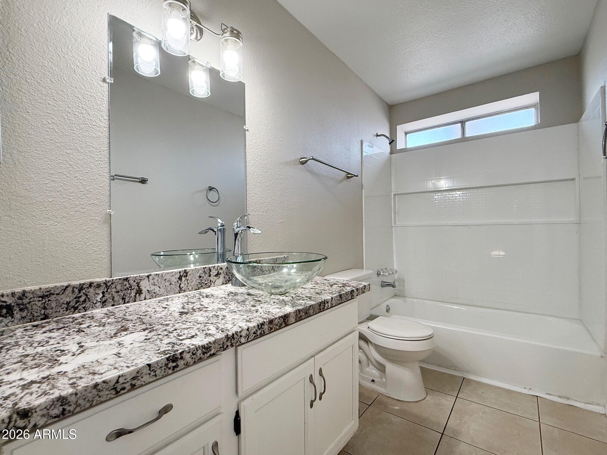 3840 North 43rd Avenue, Unit 34 Phoenix, AZ 85031 - Photo 12 of 18 a bathroom with a granite countertop sink a toilet and shower
