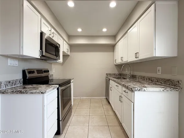a kitchen with stainless steel appliances granite countertop a stove top oven a sink a microwave and a refrigerator