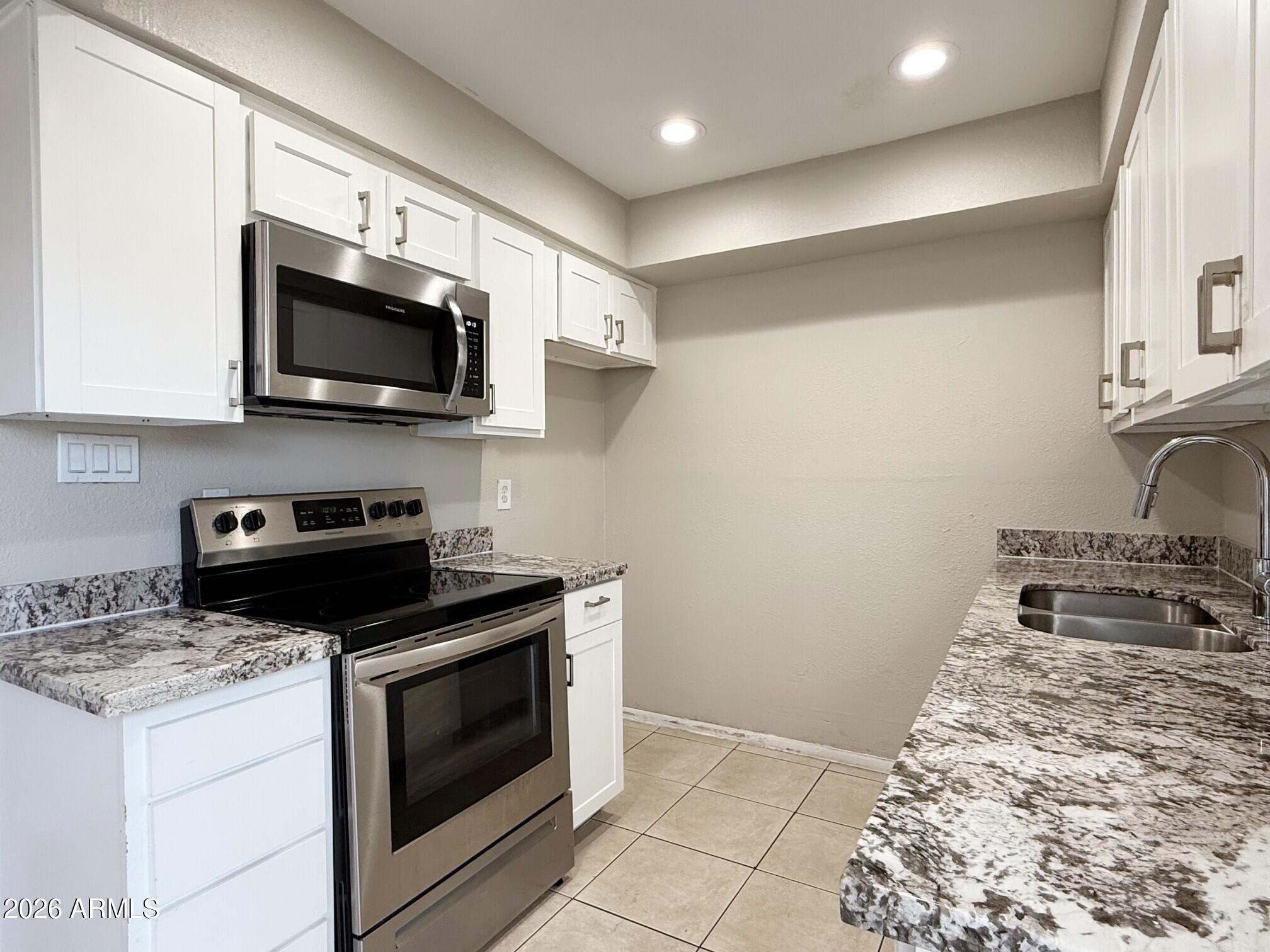 3840 North 43rd Avenue, Unit 34 Phoenix, AZ 85031 - Photo 6 of 18 a kitchen with a stove and a microwave