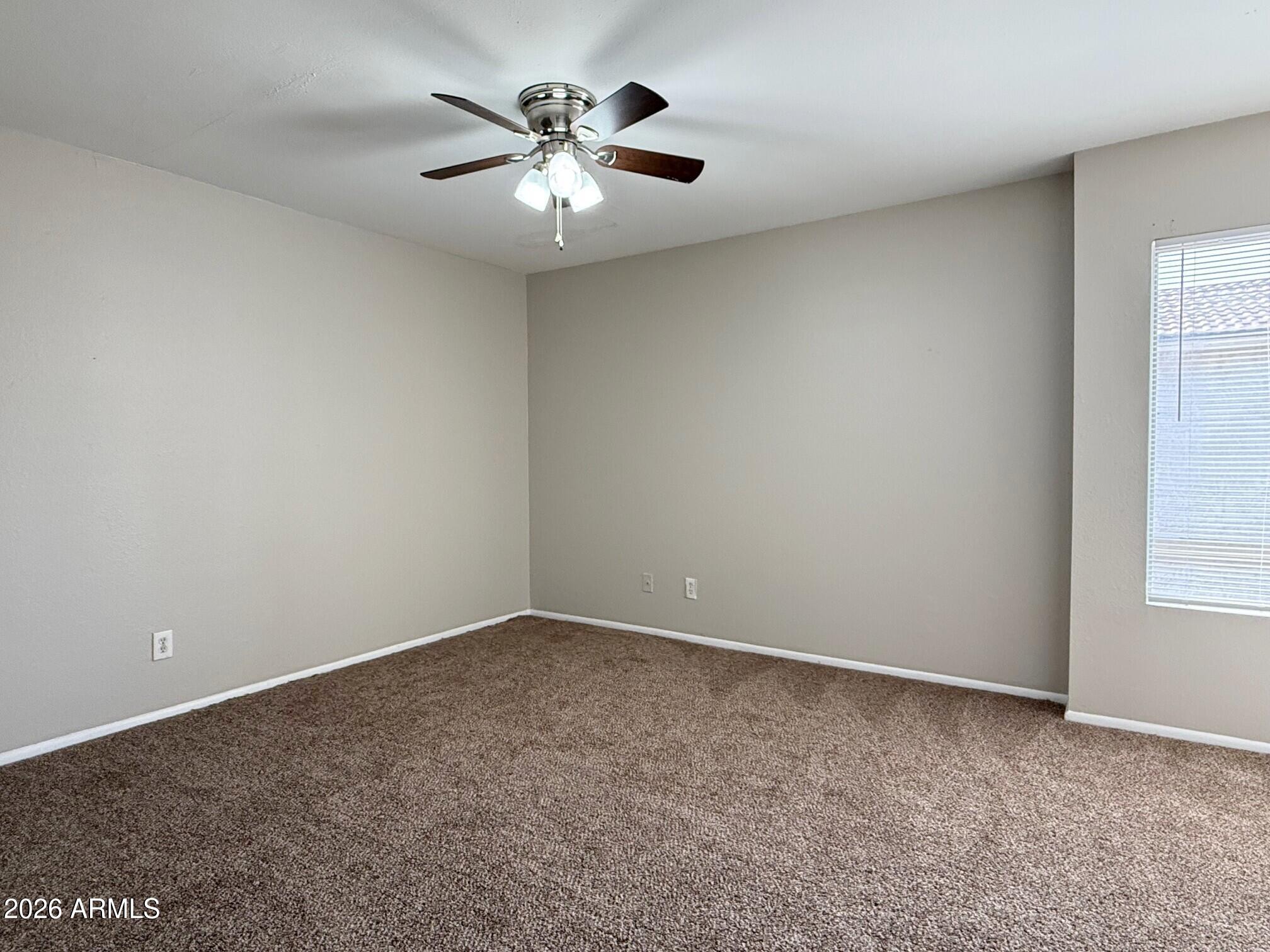3840 North 43rd Avenue, Unit 34 Phoenix, AZ 85031 - Photo 10 of 18 an empty room with a chandelier fan and windows