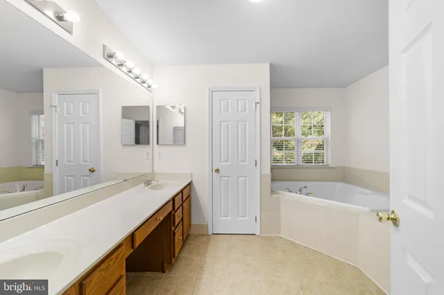 a spacious bathroom with a tub sink and mirror