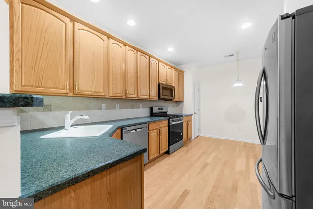 a kitchen with stainless steel appliances granite countertop a refrigerator sink and stove