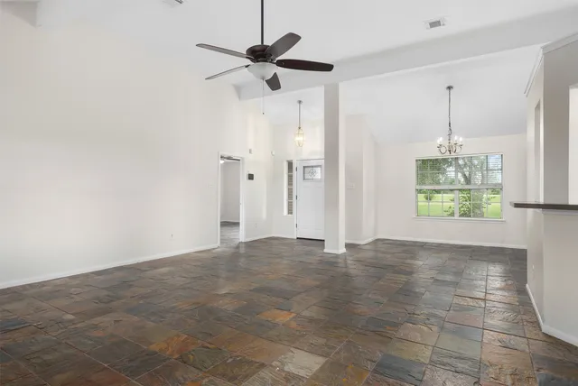 a view of an empty room and chandelier fan